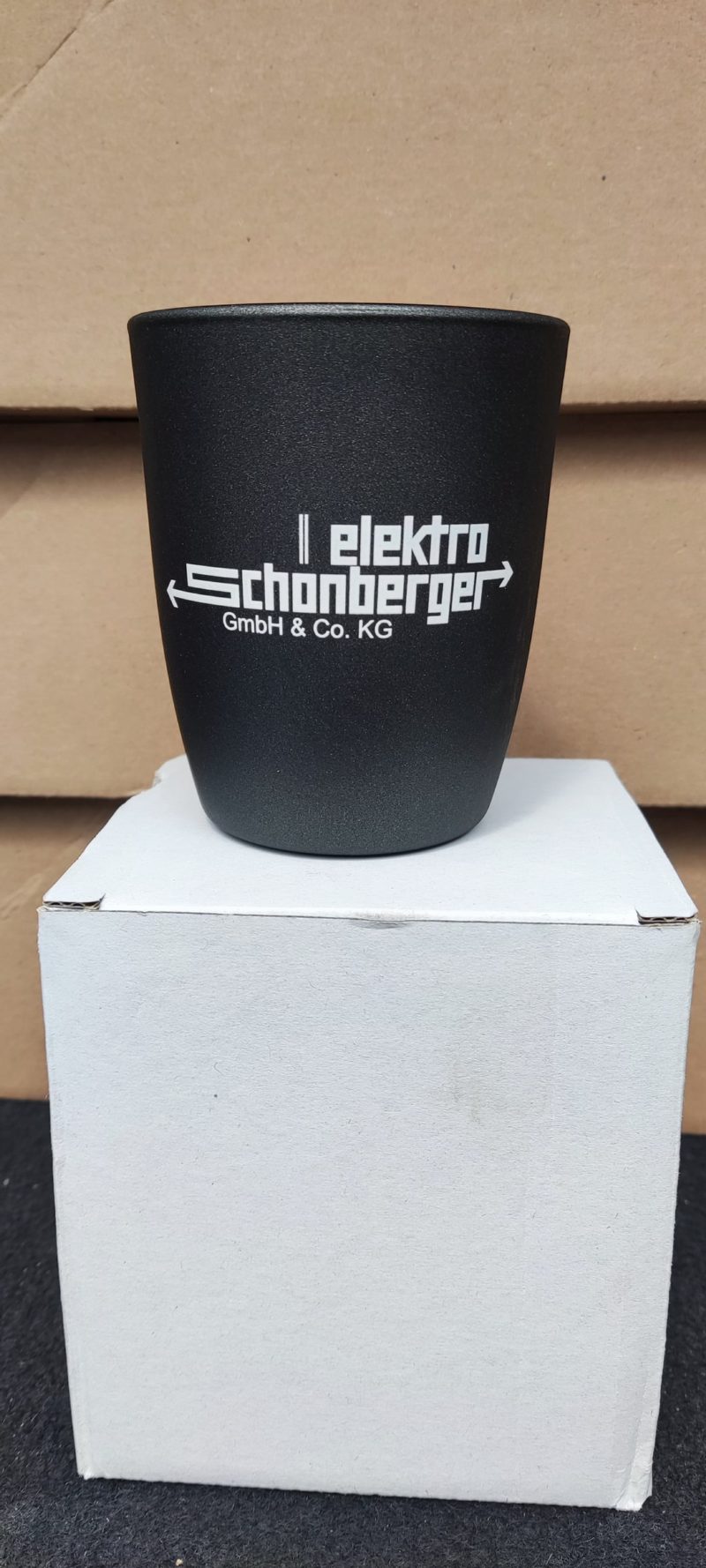 Schwarzer Becher mit weißem Firmenlogo