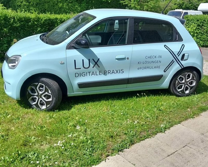 Hellblauer Kleinwagen mit Beschriftung einer Praxis