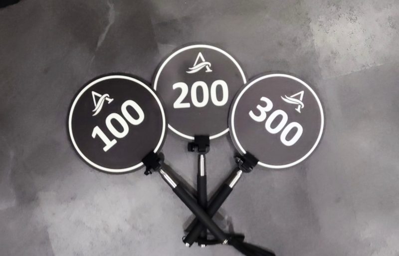 Drei runde Handschilder mit Logo und den Nummern 100, 200 und 300
