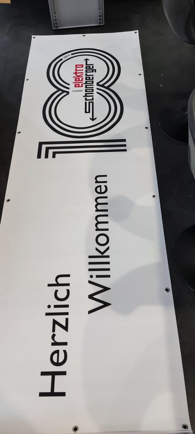 Hochformatiges weißes Schild mit großer Zahl 10 und Herzlich Willkommen