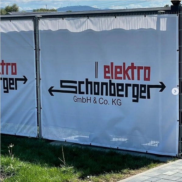 Mesh-Banner mit Firmenlogo an einem Zaun