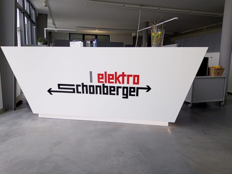 Weiße Empfangstheke mit Firmenlogo in Rot und Schwarz
