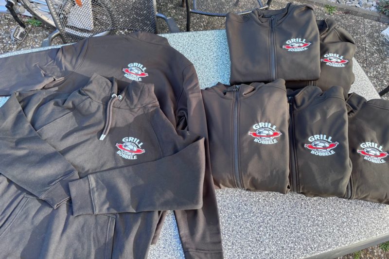 Mehrere dunkle Hoodies mit gesticktem Logo