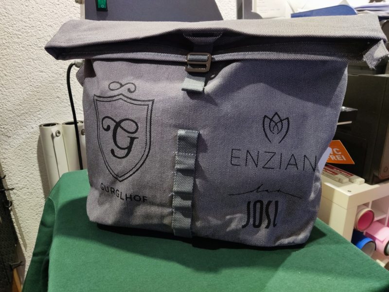 Grauer Rucksack mit mehreren Logos