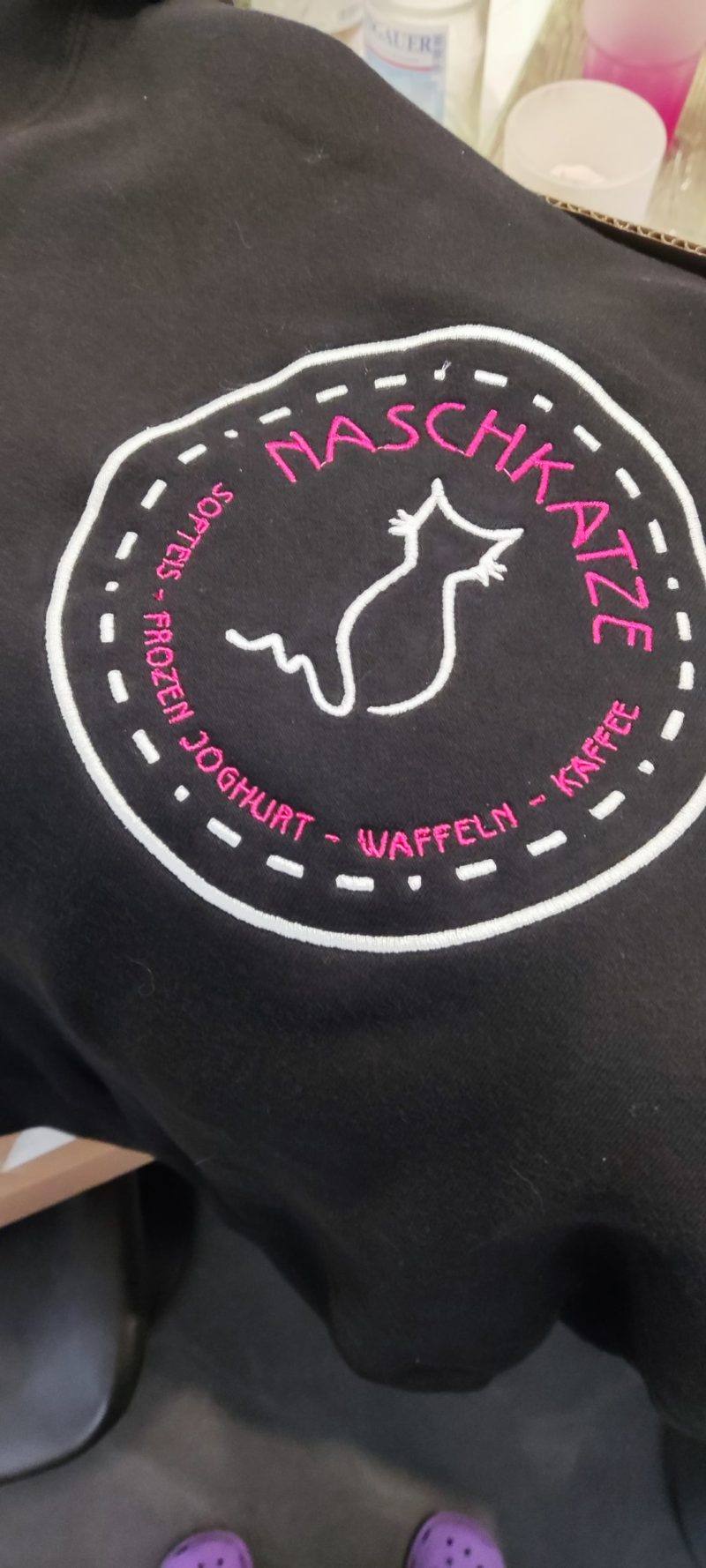 Gesticktes rundes Logo auf einem schwarzen Hoodie