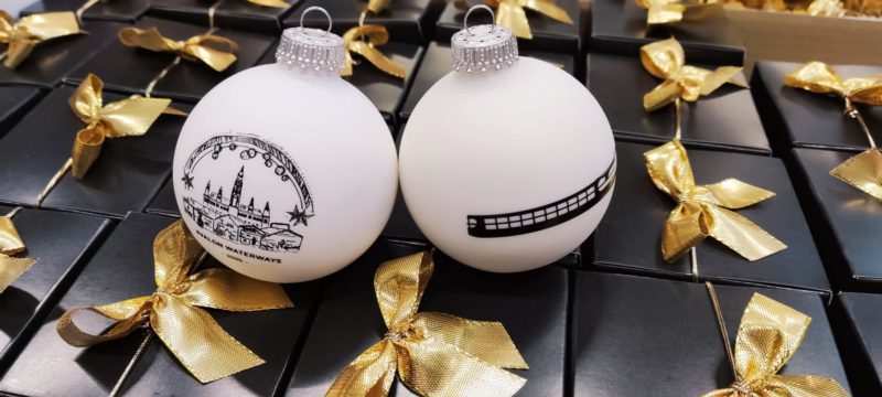 Weiße Weihnachtskugeln mit Stadtmotiv auf schwarzen Geschenkboxen
